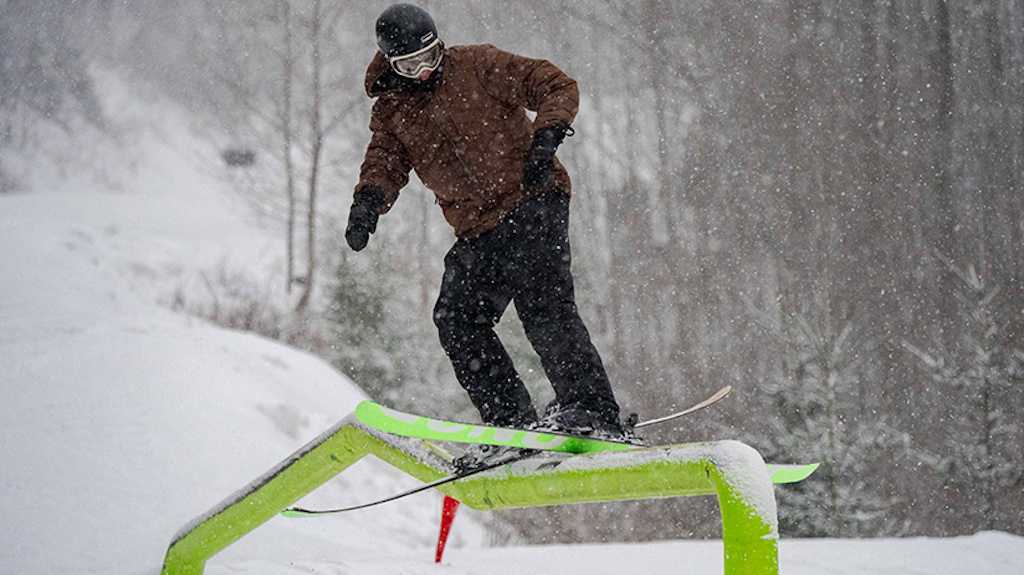 A skier slides down a kinked rail in the terrain park.